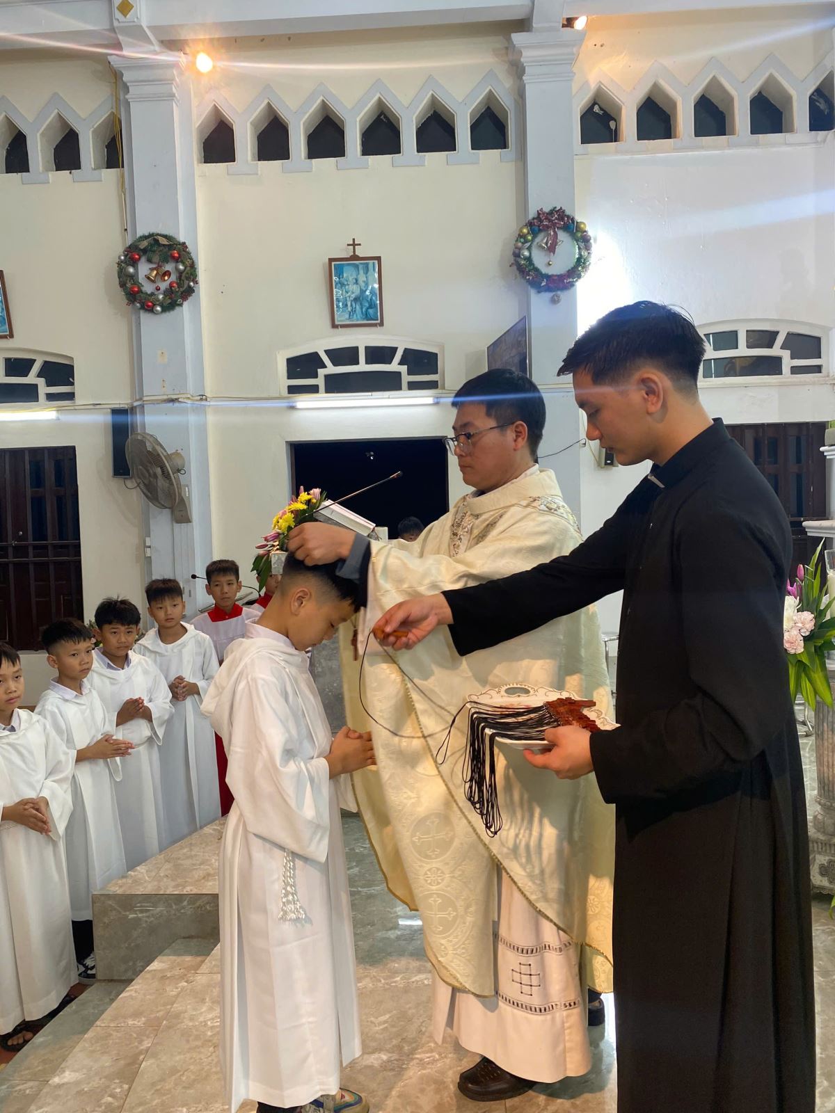 Cha xứ Phê rô trao Thánh Giá cho các em lễ sinh