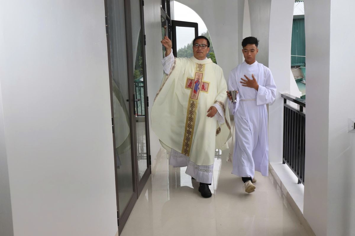 Cha xứ rảy nước thánh trên nhà mục vụ mới